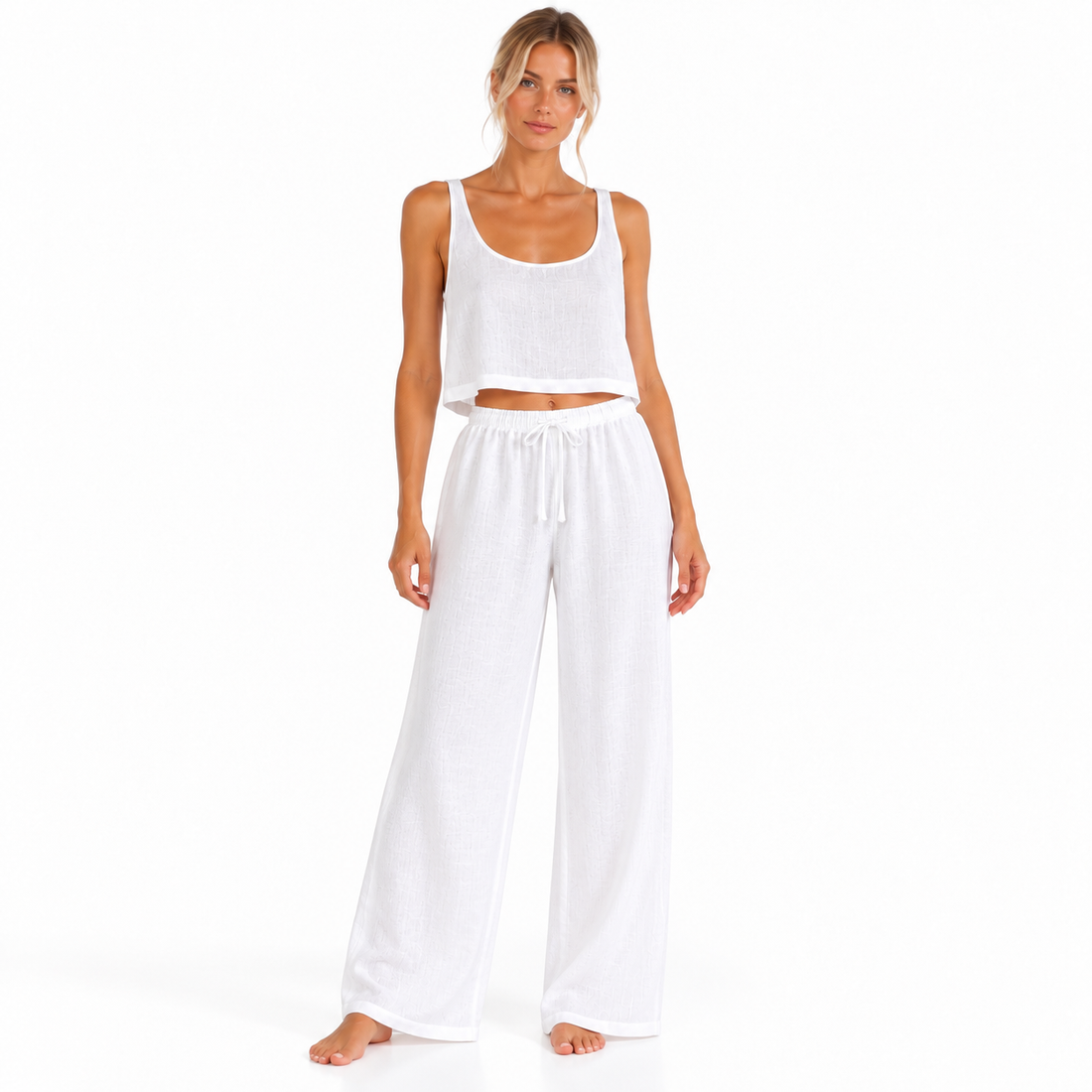 Angled view of a model wearing The Linen Travel Set by Hostess the label, with a white sleeveless crop top and wide-leg drawstring pants.